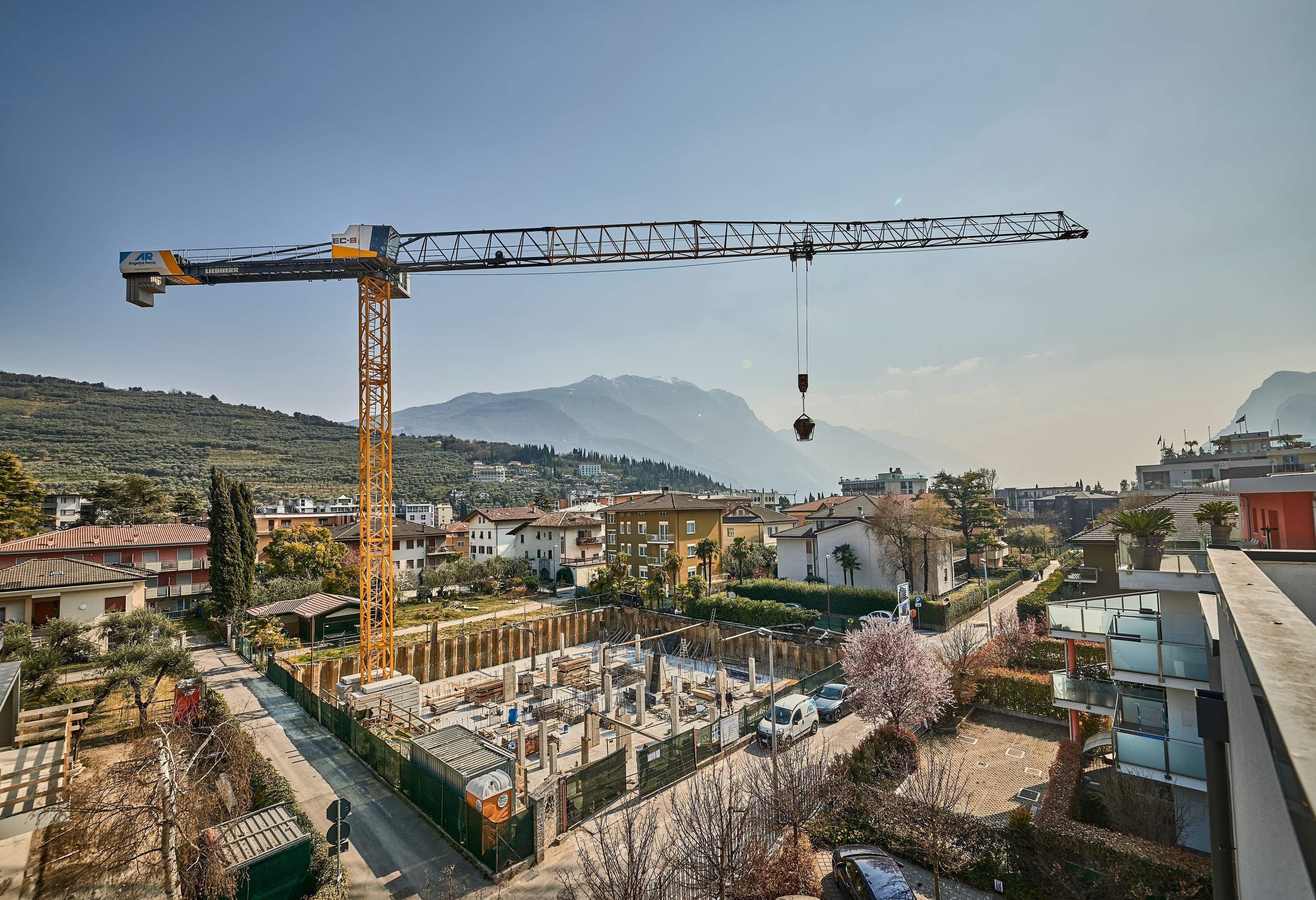 Liebherr tower crane on a construction site in Riva del Garda against the Lake Garda mountains