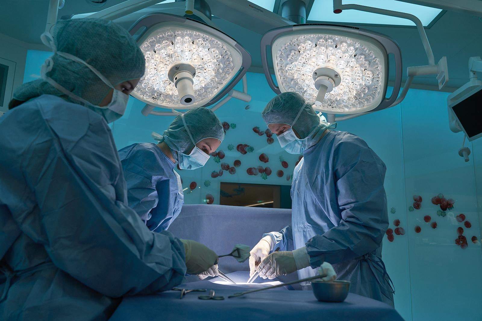 Three surgical staff operating under two marLED X lights in the OR