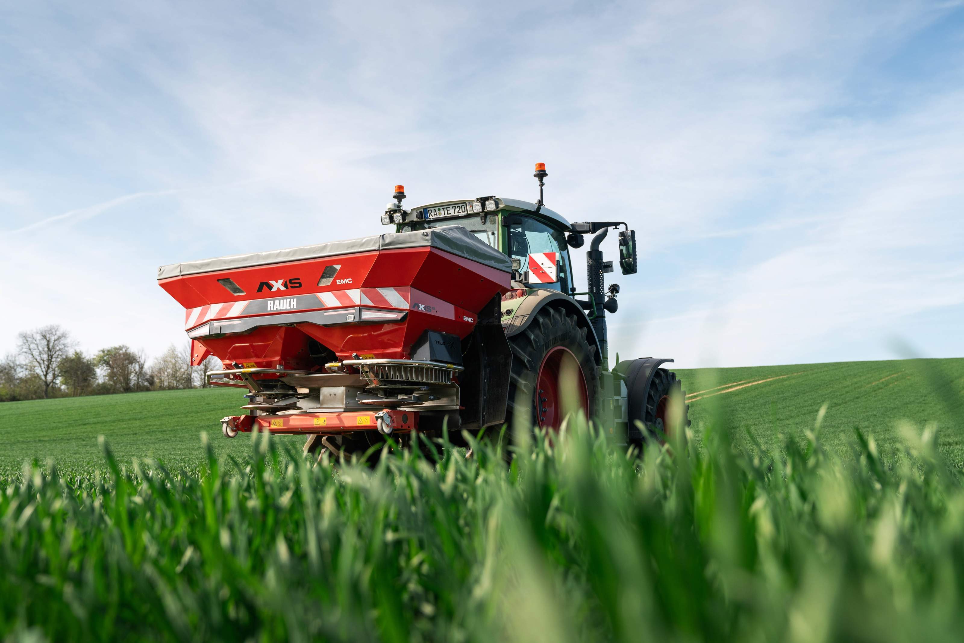 Rauch AXIS 25 fertiliser spreader mounted on a tractor in a field