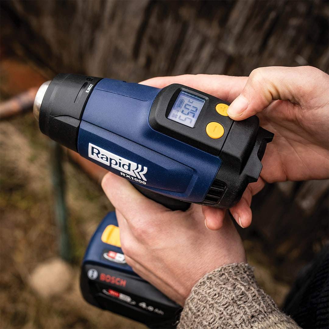 Hands operating the Rapid RX1000 hot air gun with its digital temperature display